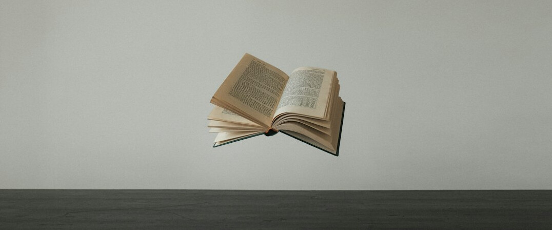 Open book and notebook on a wooden desk
